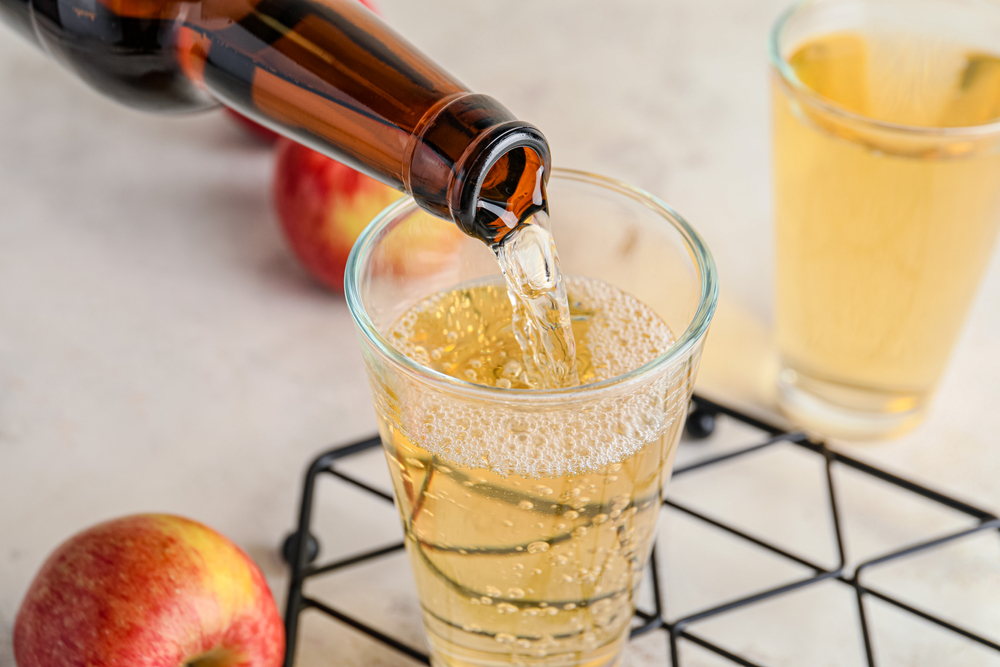 Pouring,Of,Apple,Cider,Into,Glass,On,Table